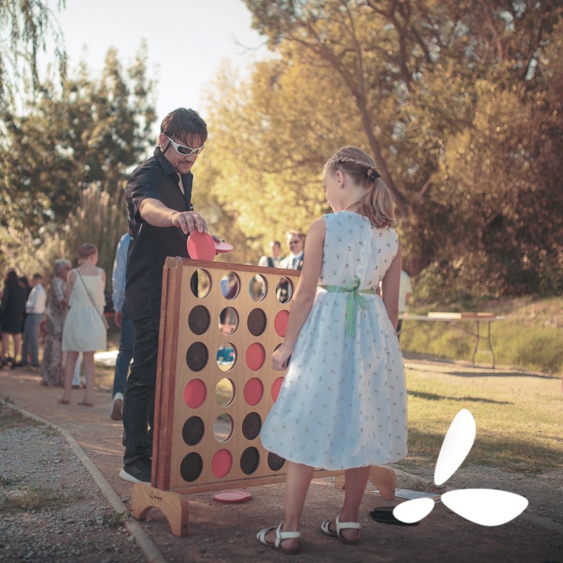 Un adulte et un enfant jouent au jeu du puissance 4 géant en bois à un mariage