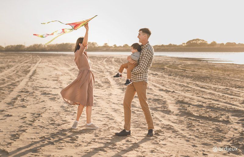 Famille jouant au cerf volant sur la plage