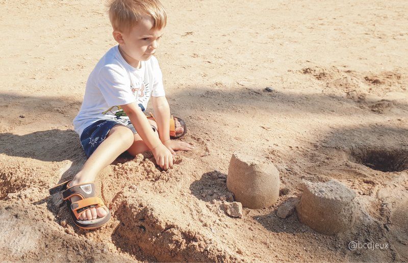 Enfant réalisant un circuit à bille sur une plage de vacances